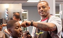 An african american male barber is cutting a man's hair