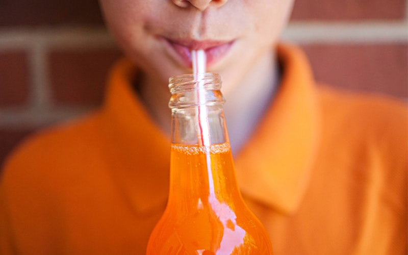 a women is drinking orange soda with a straw