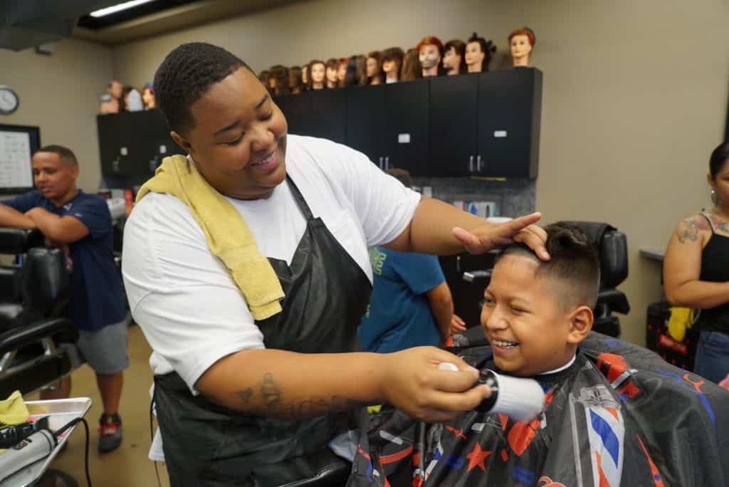 A barber student cutting a kids hair